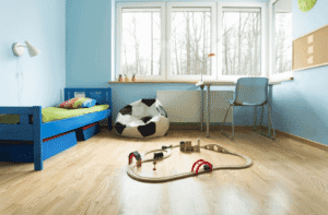 Chambre d’enfant avec parquet clair, lit et murs peints en bleu, créant une ambiance fraîche qui évoque la sensation de froid.