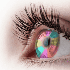 Photo en gros plan d’un œil dont l’iris est coloré en plusieurs teintes vives : rouge, vert, bleu, rose et orange. Illustrant la diversité des couleurs.