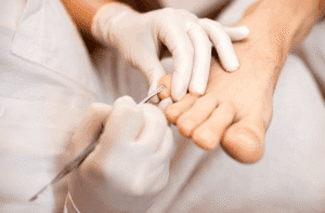 Professionnel repoussant les cuticules des ongles de pieds lors d’un soin.