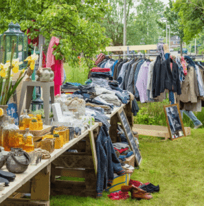 Stand de vêtements dans un vide-grenier ou vide-dressing en extérieur, type dépôt-vente.