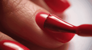 Gros plan sur un ongle de main avec un vernis rouge brillant.