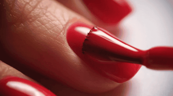 Gros plan sur un ongle de main avec un vernis rouge brillant.