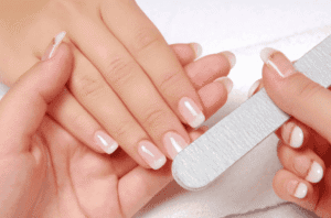 Femme se limant les ongles des mains avant la pose de vernis.