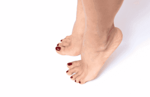 Pieds avec vernis bordeaux appliqué sur les ongles, posés sur un fond blanc.