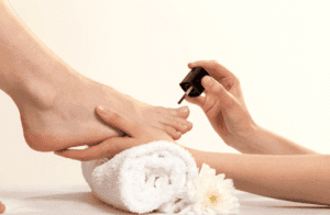 Application d’un vernis transparent sur les ongles des pieds en institut de beauté.