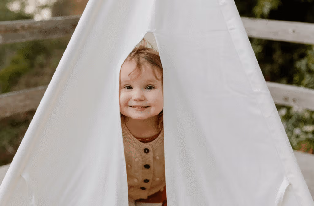 Enfant souriant et jouant dans une petite tente blanche. "Une image vaut mille mots".