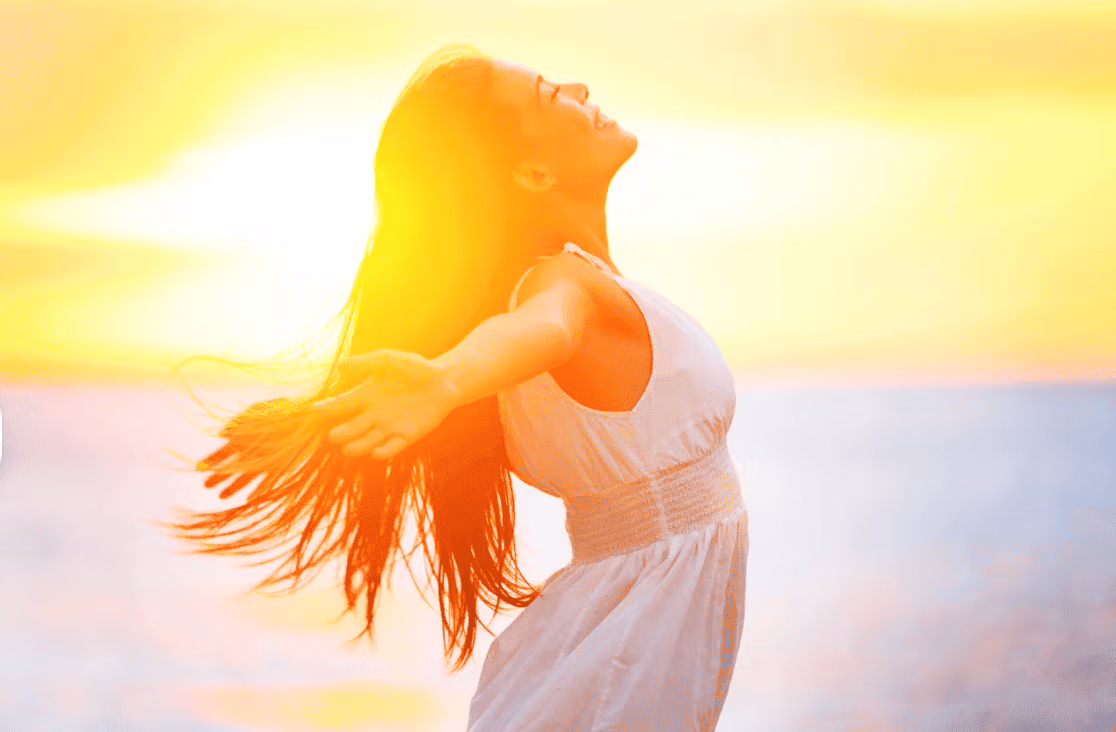 Jeune femme joyeuse à la plage au moment du coucher du soleil.