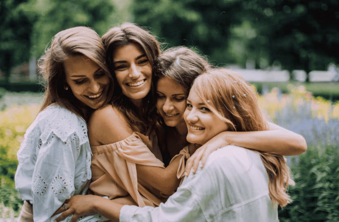 Quatre jeunes filles souriantes se prenant dans les bras.