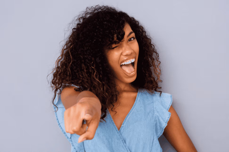 Jeune femme souriante pointant du doigt avec enthousiasme.