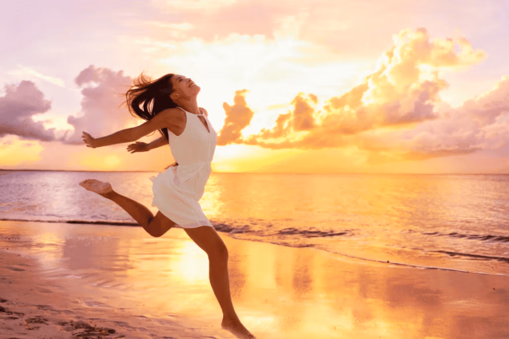 Femme courant sur la plage au coucher du soleil, souriante et épanouie.