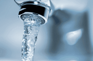 Photo montrant de l’eau claire s’écoulant d’un robinet, soulignant l’importance de bien s’hydrater durant la saison estivale.