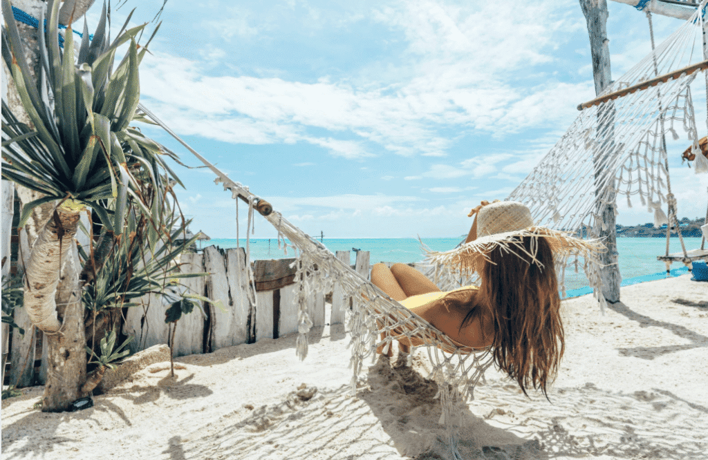 Femme détendue sur un hamac à la plage, profitant du soleil, importance de se protéger du soleil.